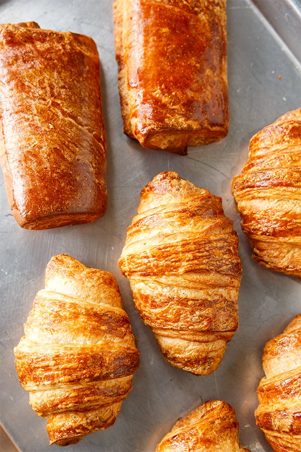 Fresh croissants and pain au chocolat on a baking tray
